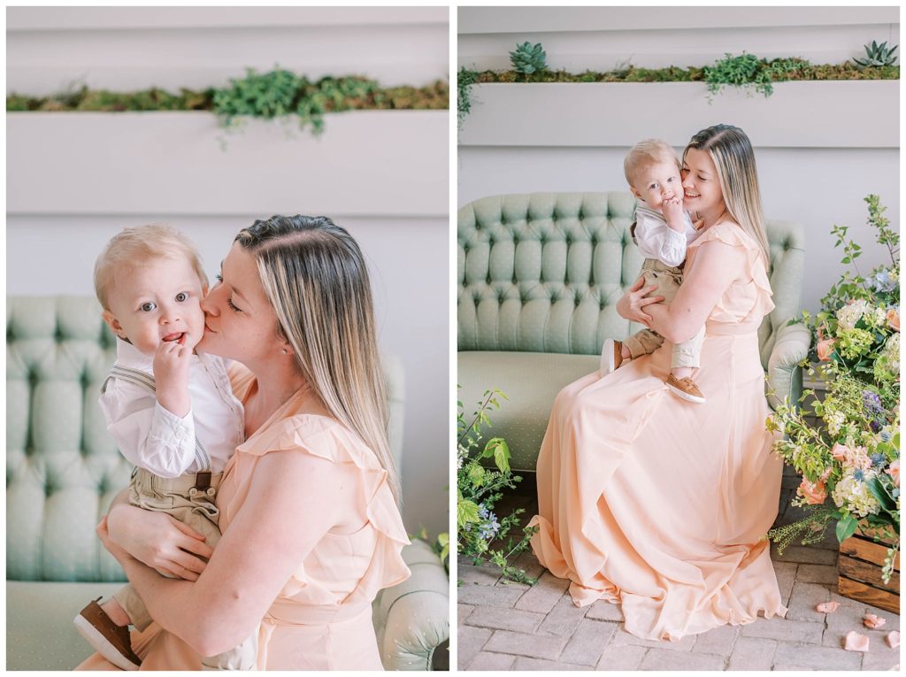 mom wearing a pink dress holding her small son on a green couch