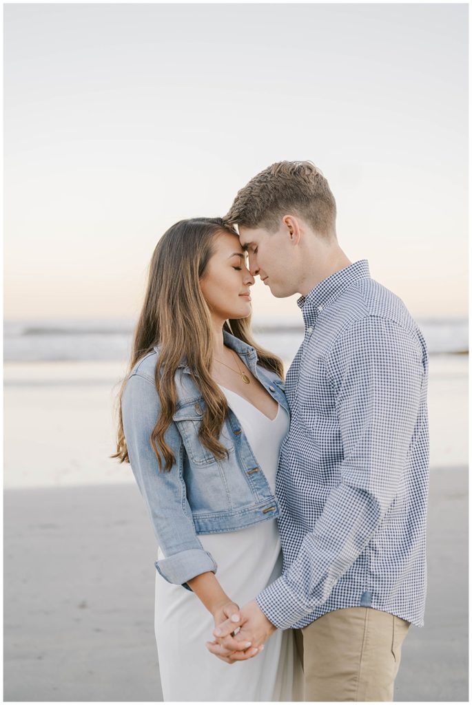 couple touching foreheads at beach at sunset