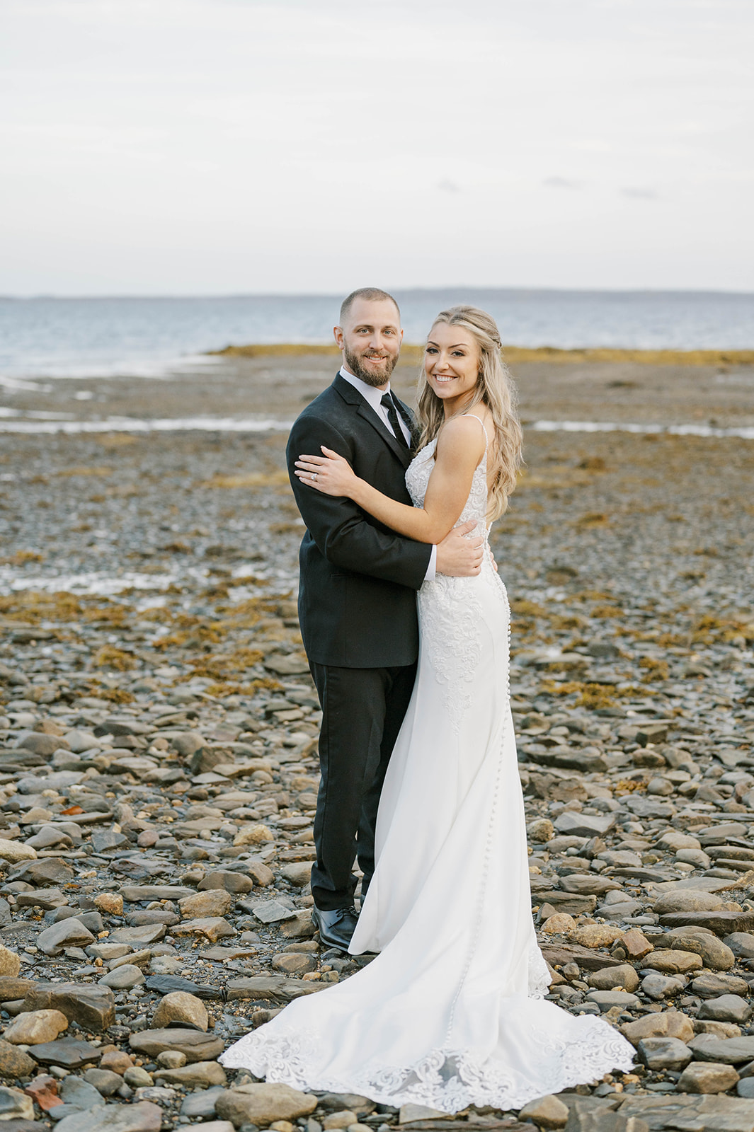 wedding couple standing on the rocks at the beach in Maine