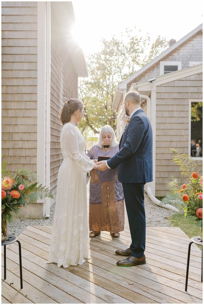 bride and groom holding hands during wedding ceremony in Maine