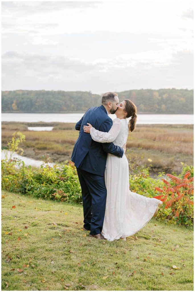 groom kissing bride near the ocean in Maine
