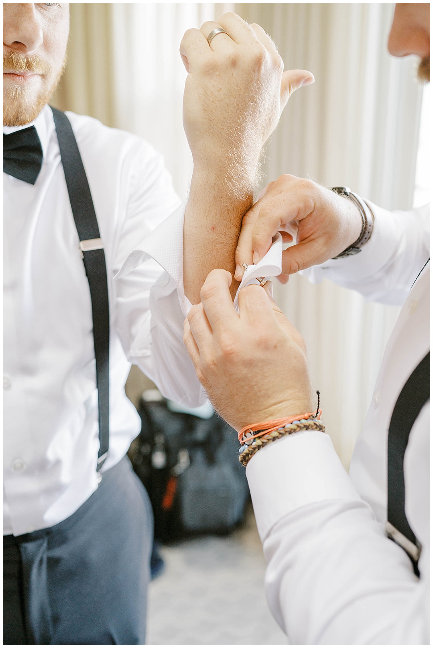 groom putting on his airplane cufflinks at Maine wedding