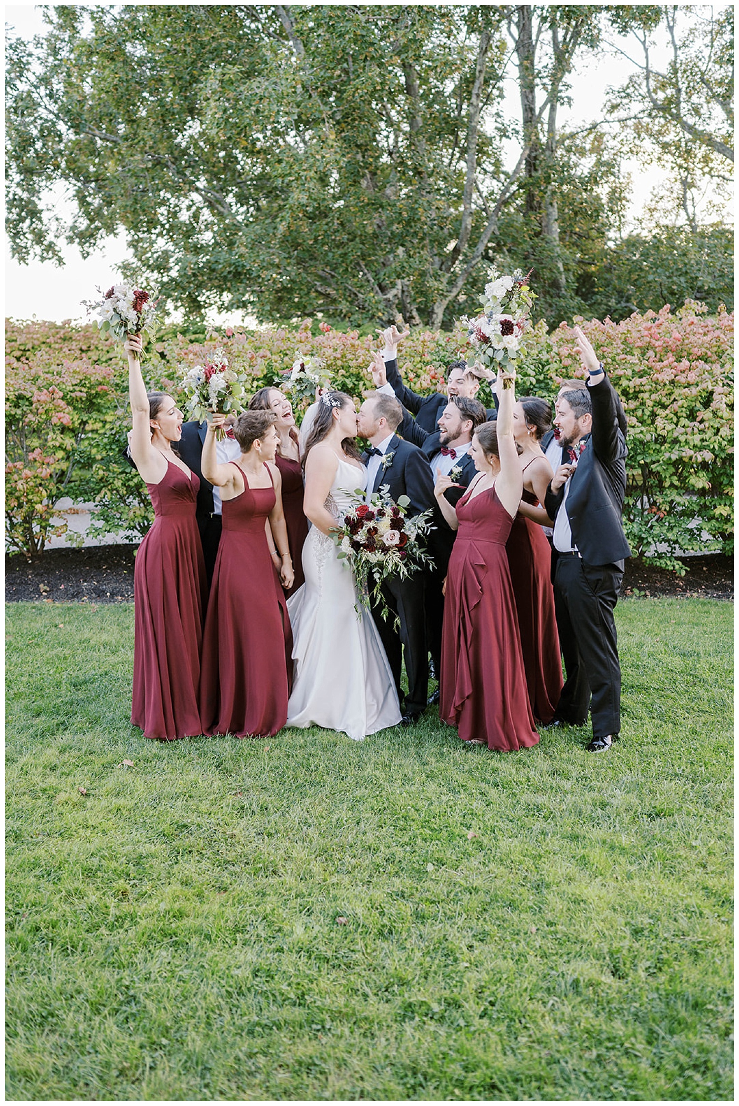 bride and groom kissing with bridal party cheering