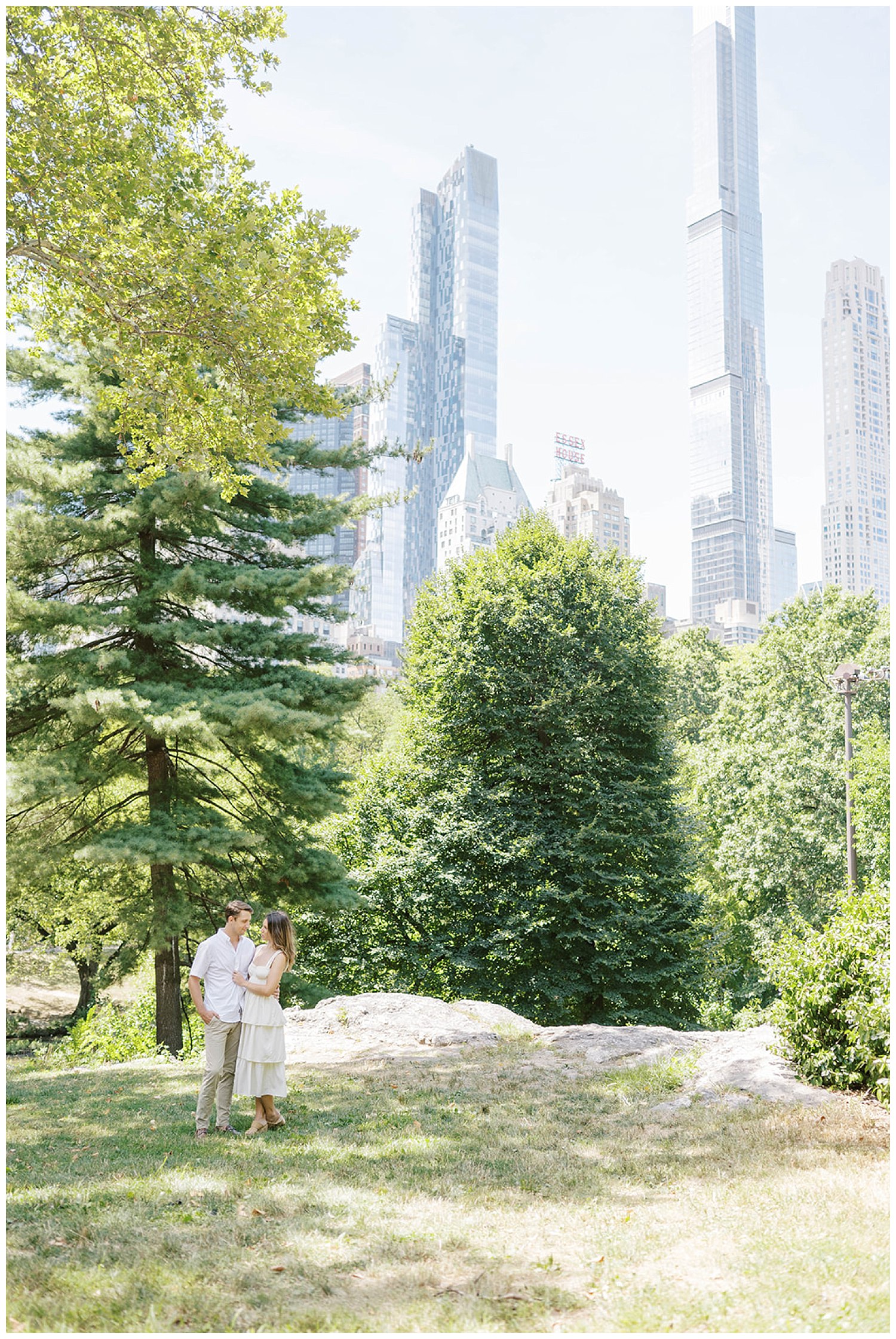 couple posing together in Central Park with New York skyline in the background