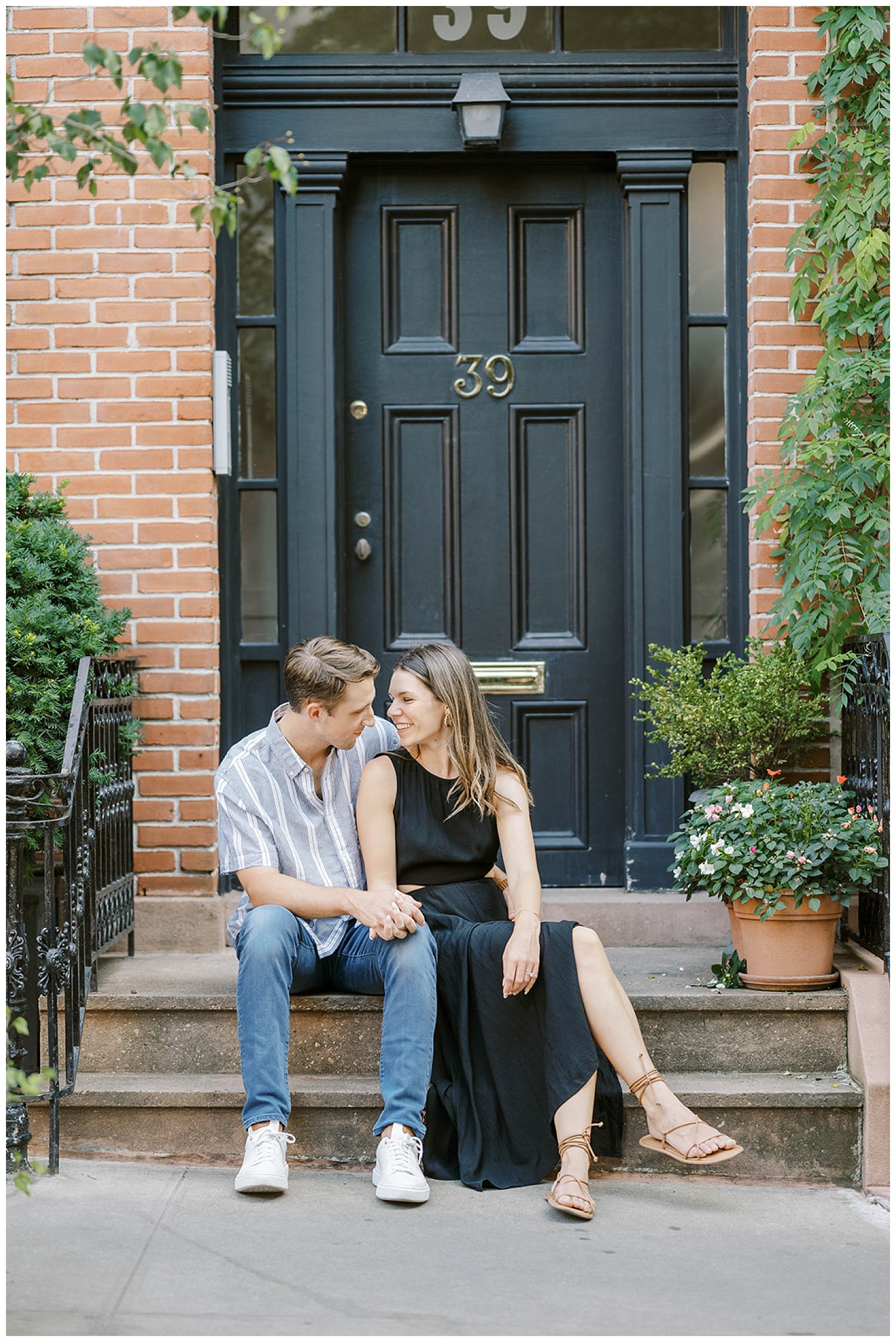 engaged couple sitting on the front steps of a brownstone in New York City