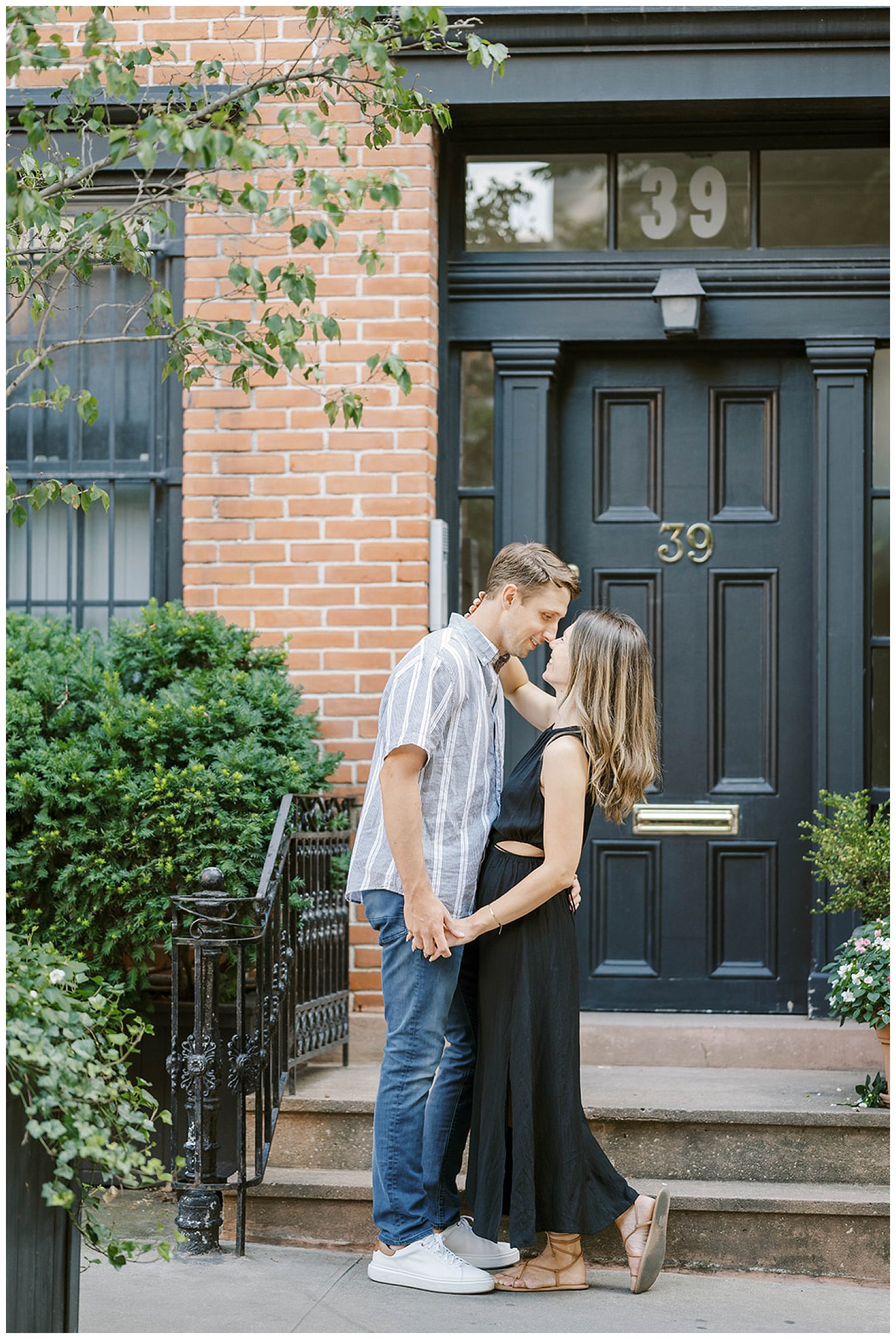 engaged couple standing in front steps of a brownstone in New York City