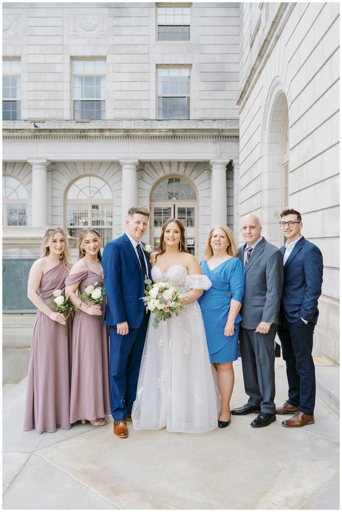 wedding couple posing with family outside Portland City Hall