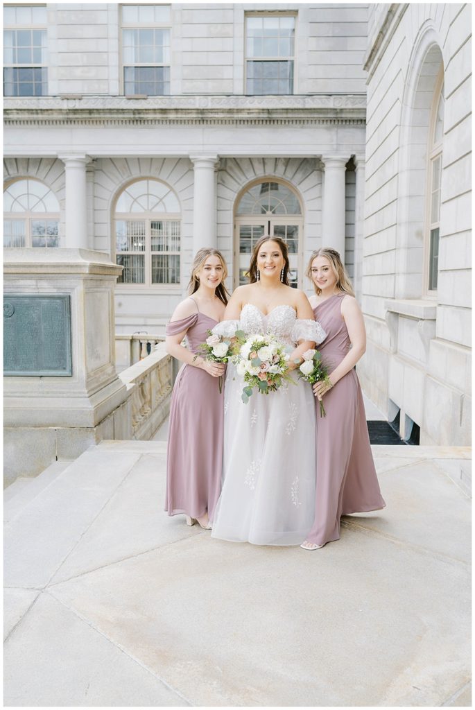 bride posing with bridesmaids outside Portland City Hall