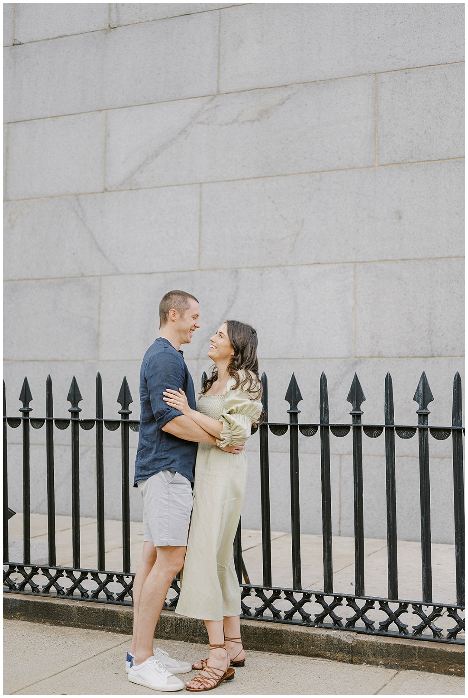 engaged couple posing in front of black fence at Monument Square in Boston