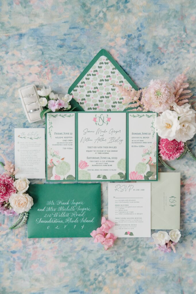 Flat lay of invitations with pink and green details, photographed on soft linen