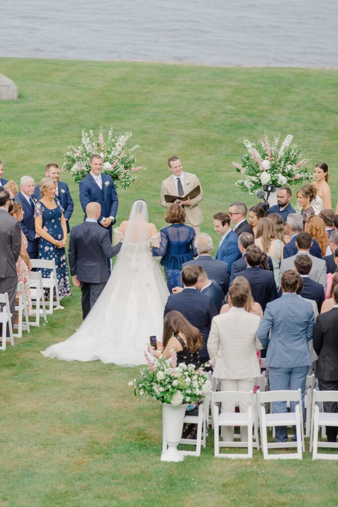 Elegant floral arrangements framing a serene waterfront ceremony view.