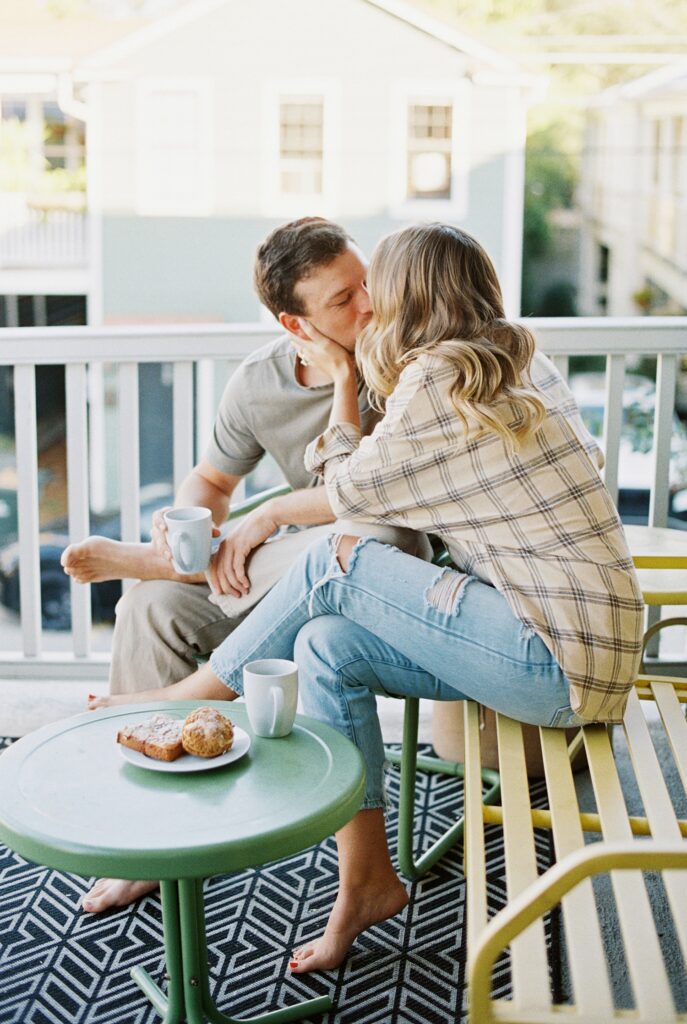 couple kiss while enjoying breakfast on their porch