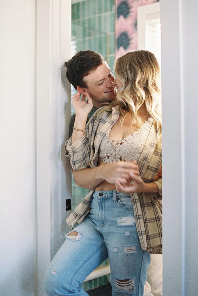 couple kiss in doorway of home during engagement session