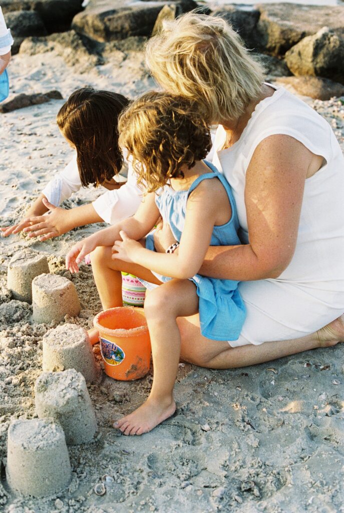 kids playing with grandparents at the beach building sand castles