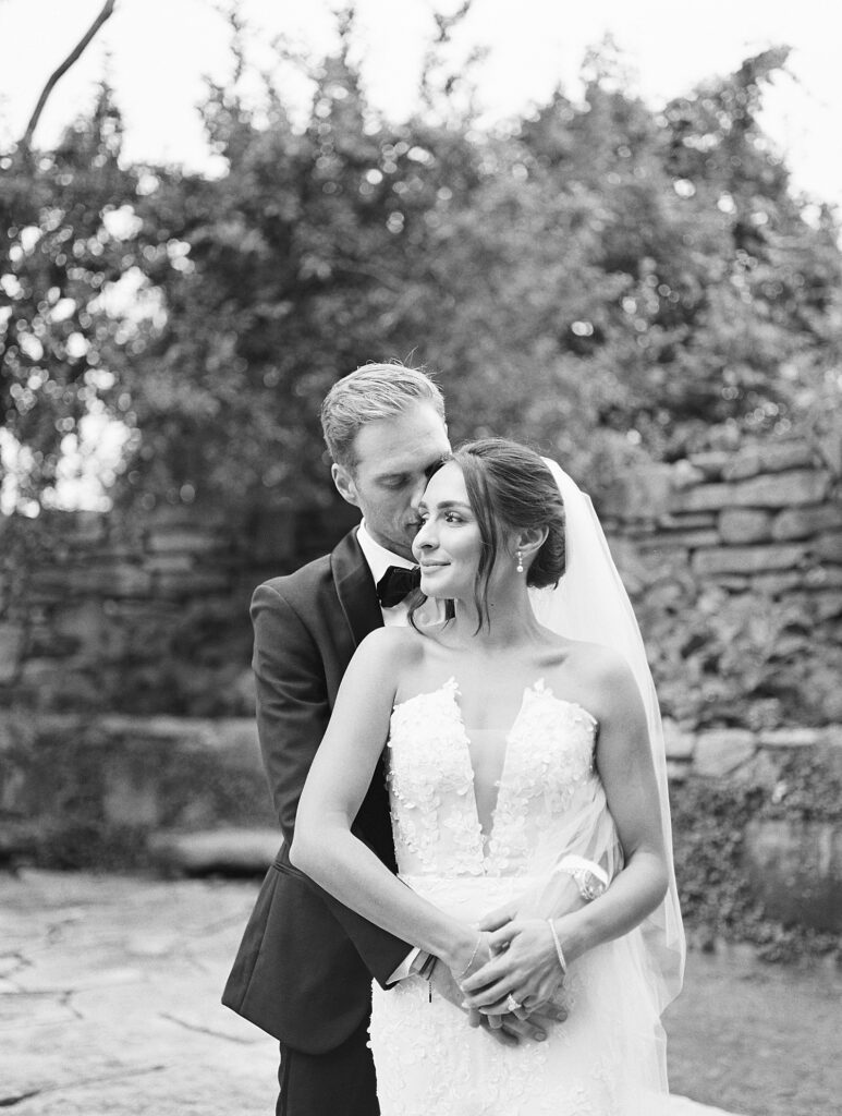 groom whispers in his bride's ear from behind 