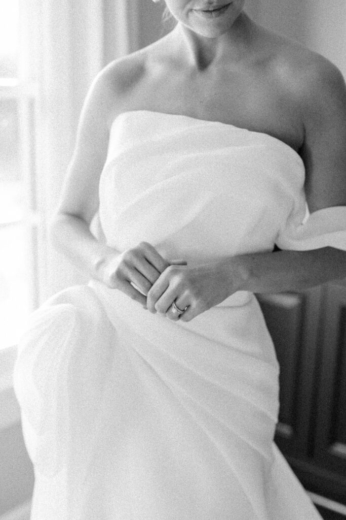 bride delicately holds her hands in front of herself in a grecian shift dress