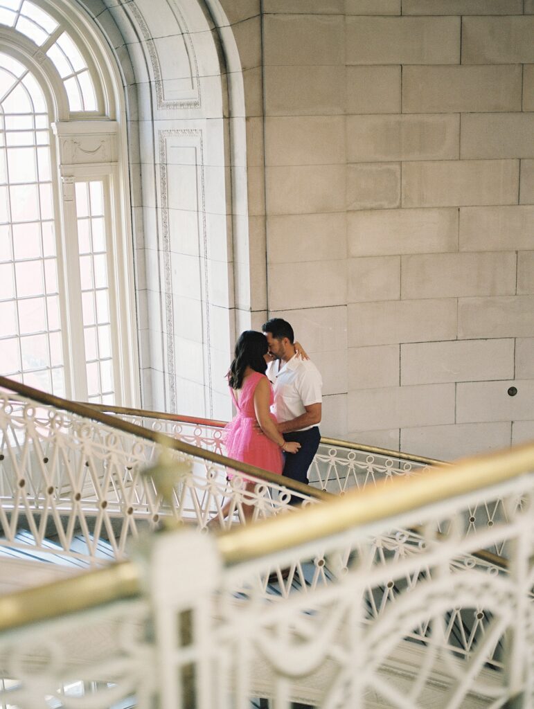 couple hold each other close on stair well in gallery