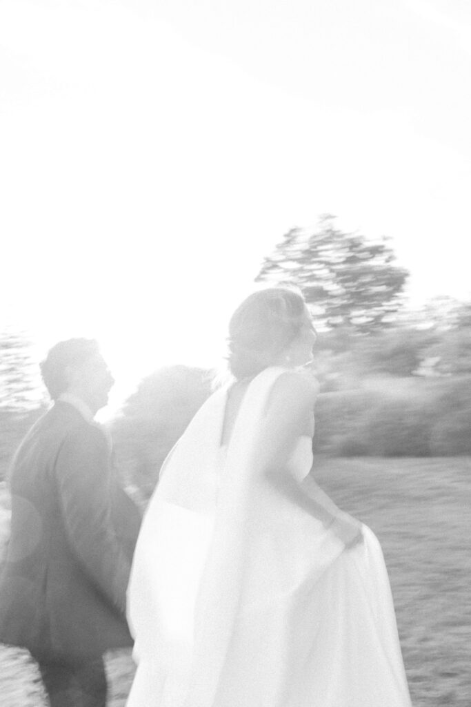 Romantic black and white photo of bride and groom embracing beneath the arbor