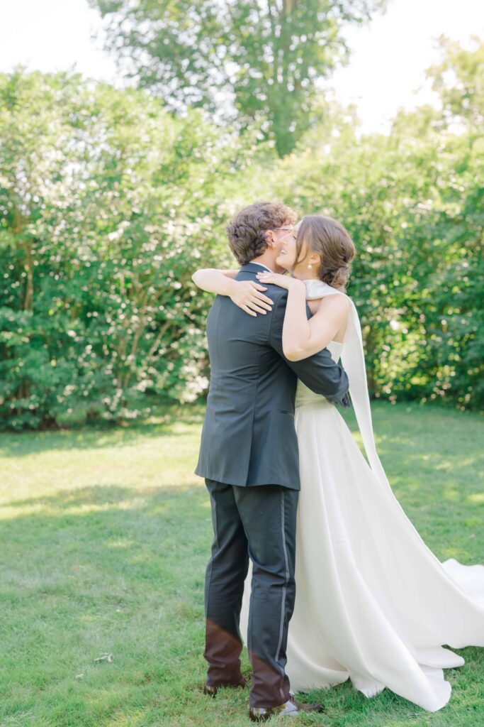 Couple sharing their first kiss in front of guests at Aldworth Manor’s stone terrace altar
