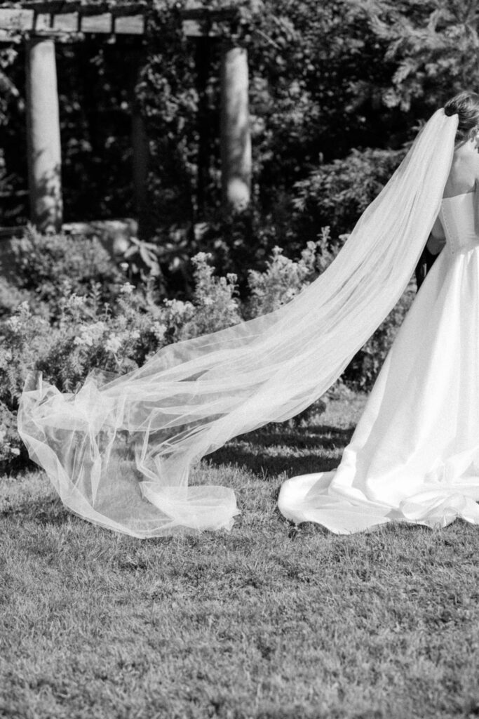 Bride walking down the aisle with her veil trailing behind on the stone walkway