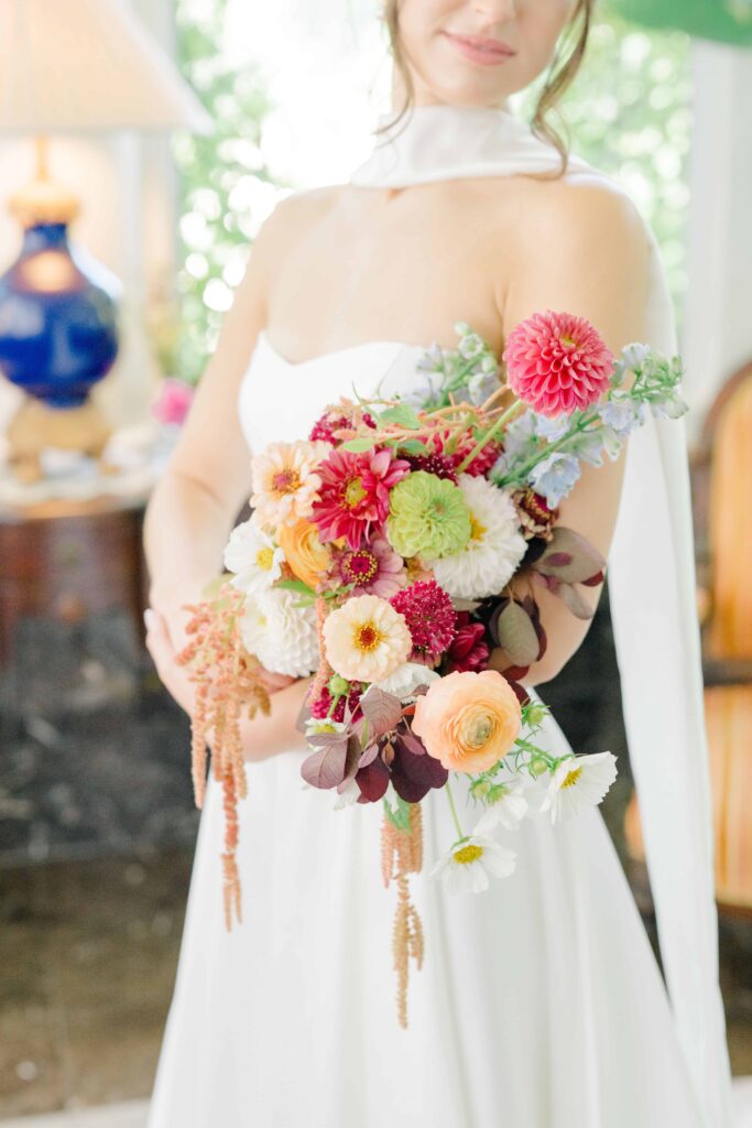 Colorful wildflower-inspired bridal bouquet with textured blooms and greenery resting on stone steps at Aldworth Manor