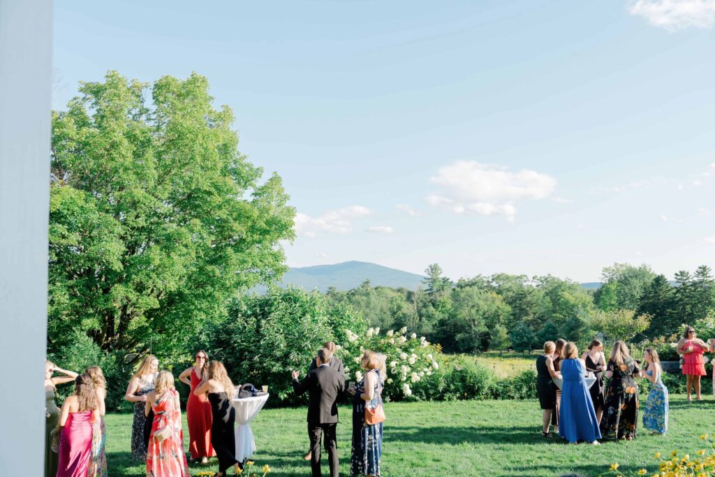 Guests mingling during cocktail hour on the lawn with passed drinks and summer breeze