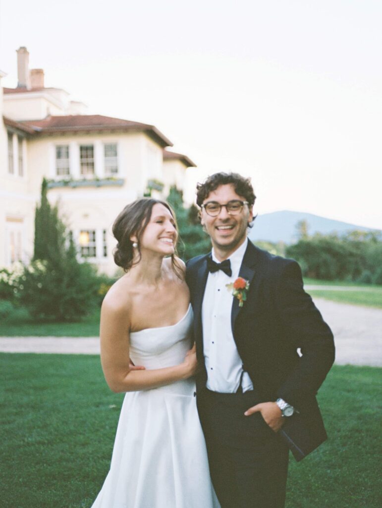 Bride and groom walk hand-in-hand through the gardens of Aldworth Manor at sunset, surrounded by golden light