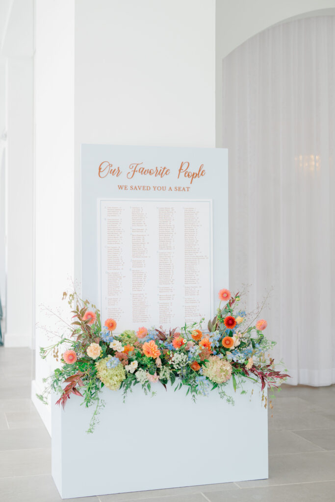 Floral-adorned wedding seating chart display reading "Our Favorite People" at Belle Mer wedding reception.
