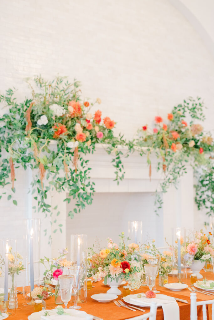 Belle Mer wedding reception fireplace with lush fall floral installation and reception tables.