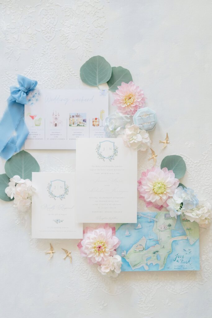 Flat lay of watercolor invitation suite, pearl veil, and heirloom details for a coastal wedding at Eisenhower House in Newport, Rhode Island