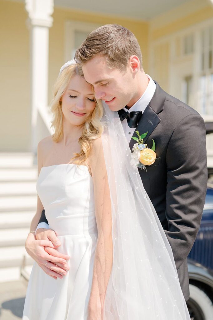 First look between bride and groom under a tree overlooking Narragansett Bay at Eisenhower House Newport Rhode Island.