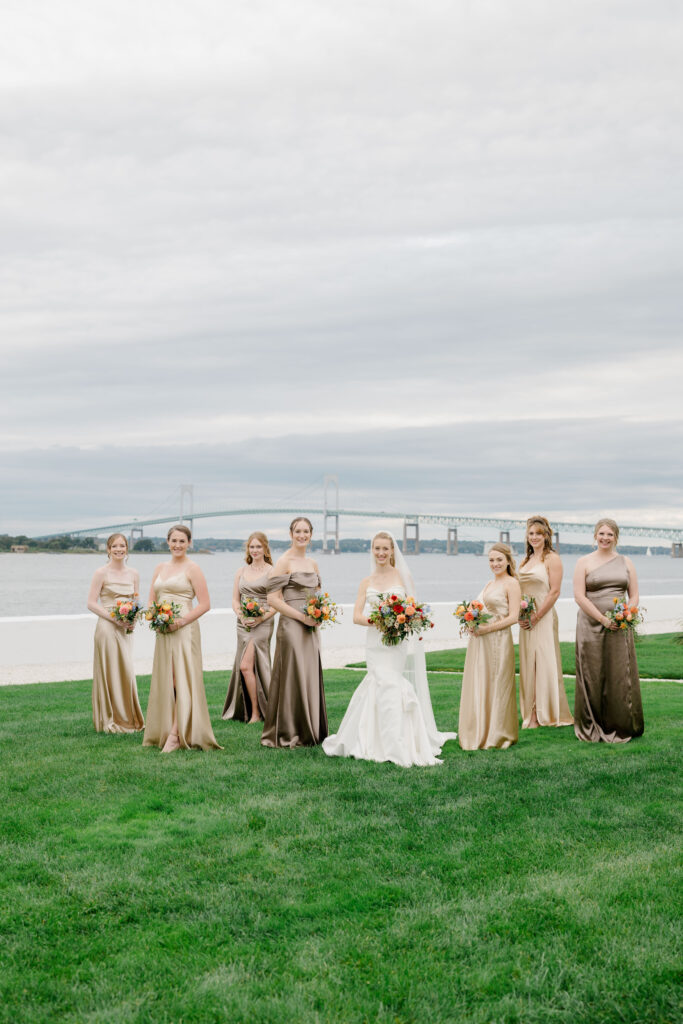Bride with bridesmaids on Belle Mer lawn with view of Newport Bridge in background.