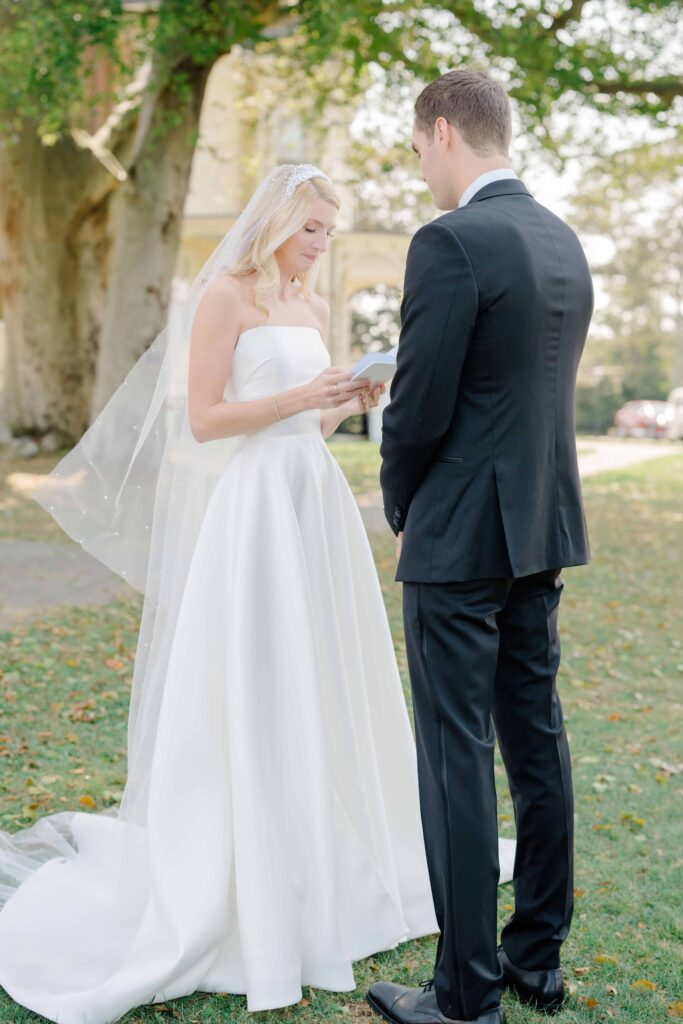 Emotional first look under a tree outside Eisenhower House with Narragansett Bay in the background.
