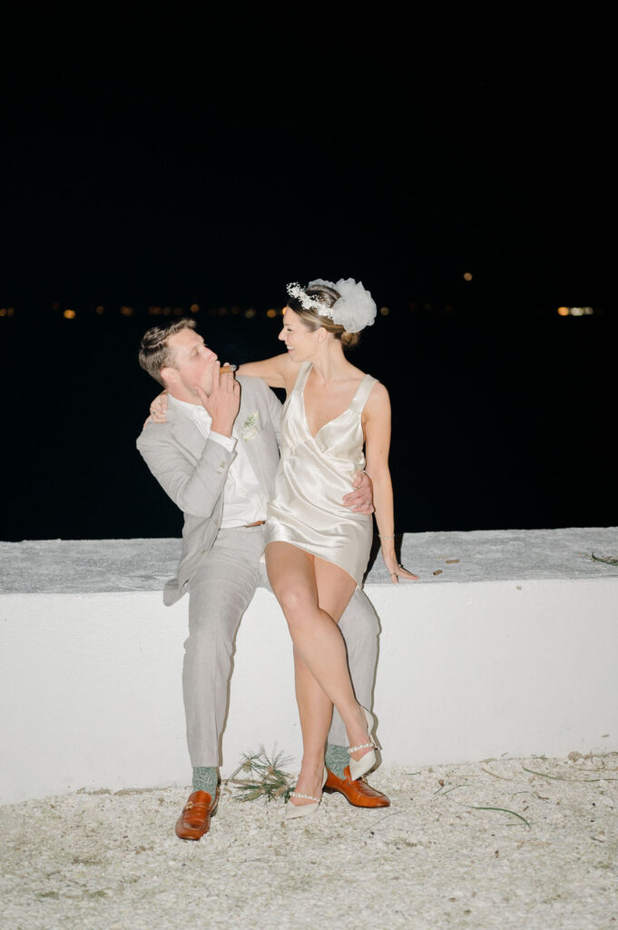 Stylish nighttime flash portrait of bride and groom in reception attire at Belle Mer waterfront.