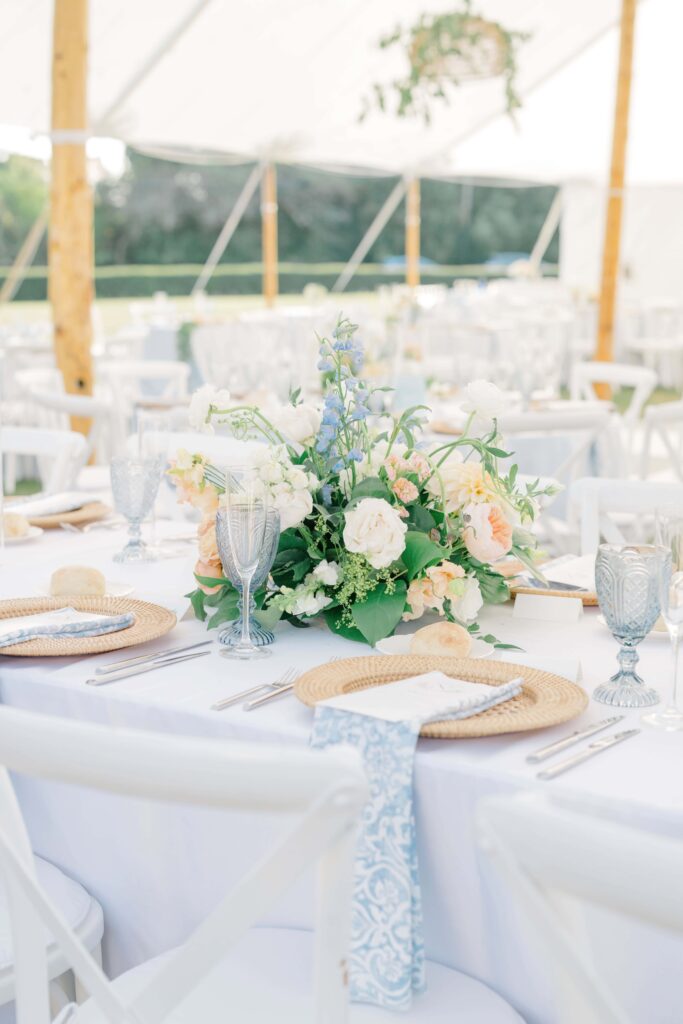Custom crest table number set among garden-inspired florals and woven chargers.