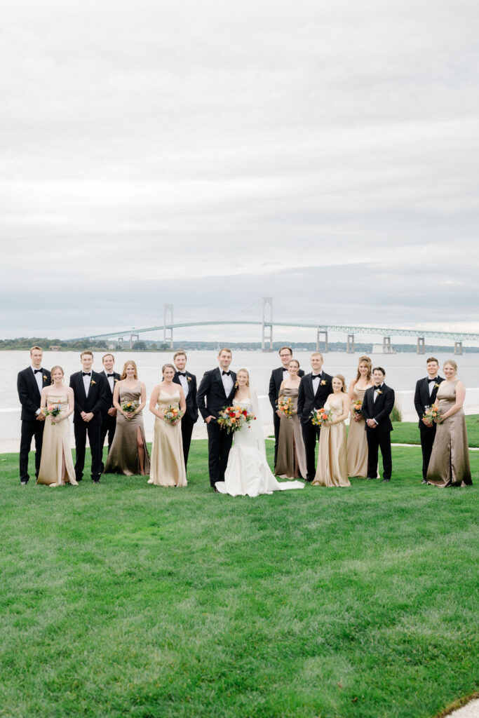 Full wedding party with bride and groom on Belle Mer lawn with waterfront views.