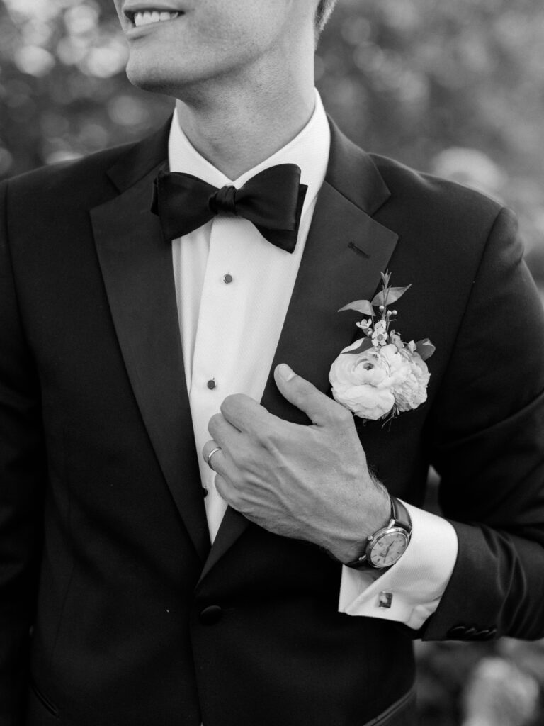 Groom adjusting his black tuxedo in natural light before ceremony at Eisenhower House.