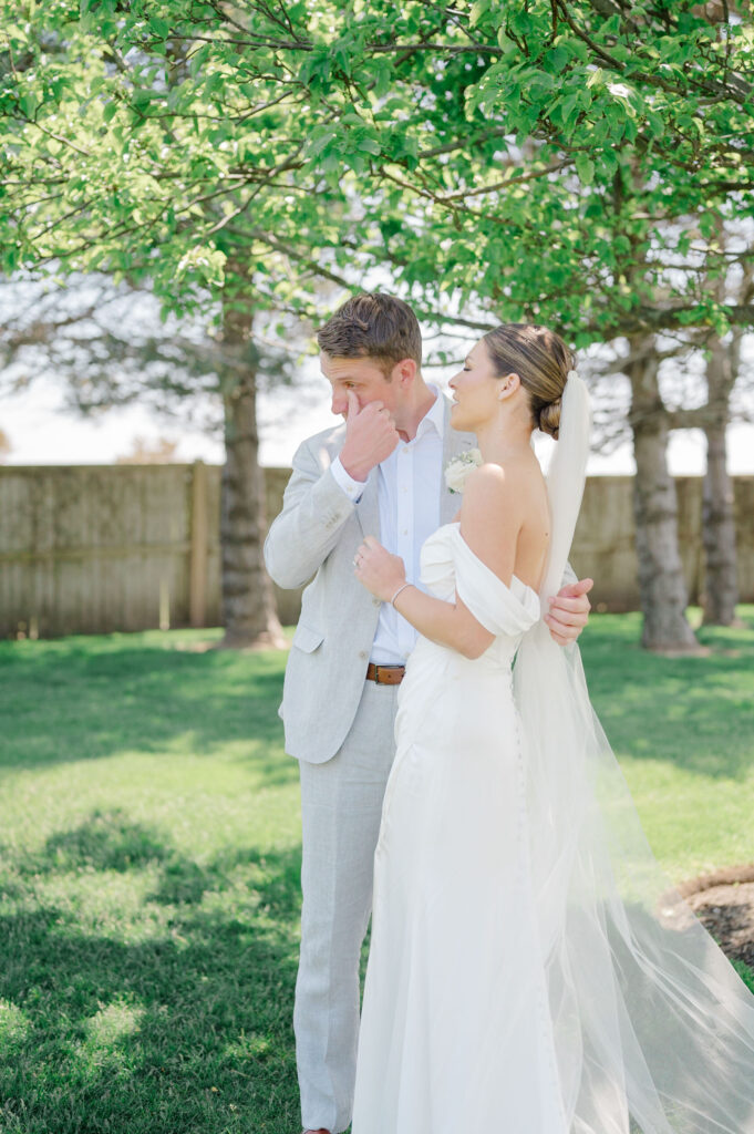 Emotional first look between bride and groom under trees at Belle Mer, Newport wedding venue.