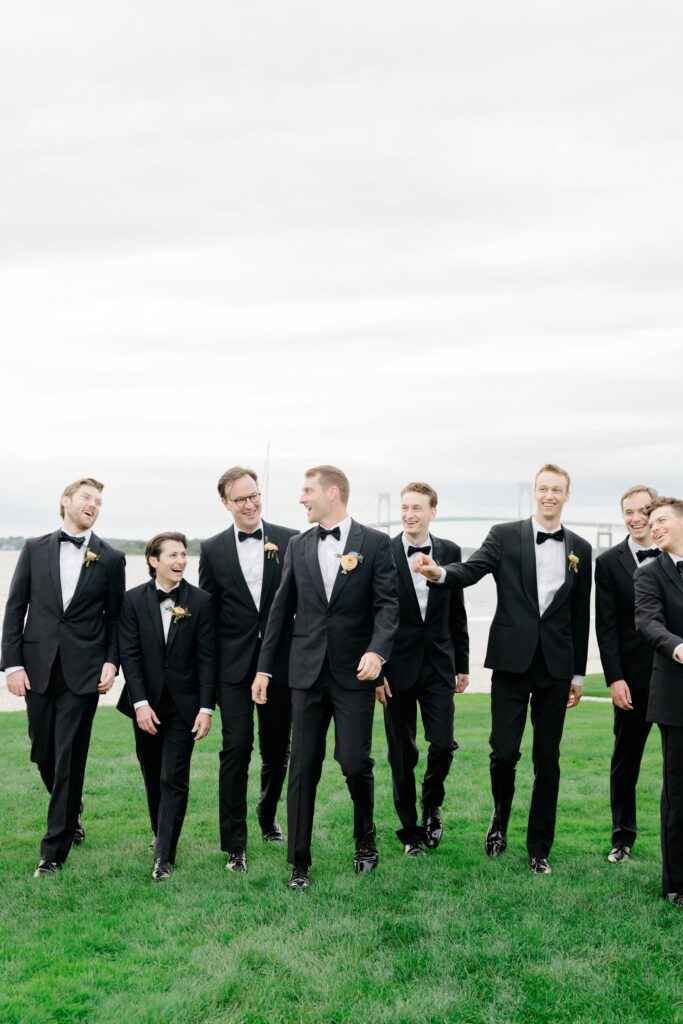 Groomsmen laughing and walking during Belle Mer wedding portraits.