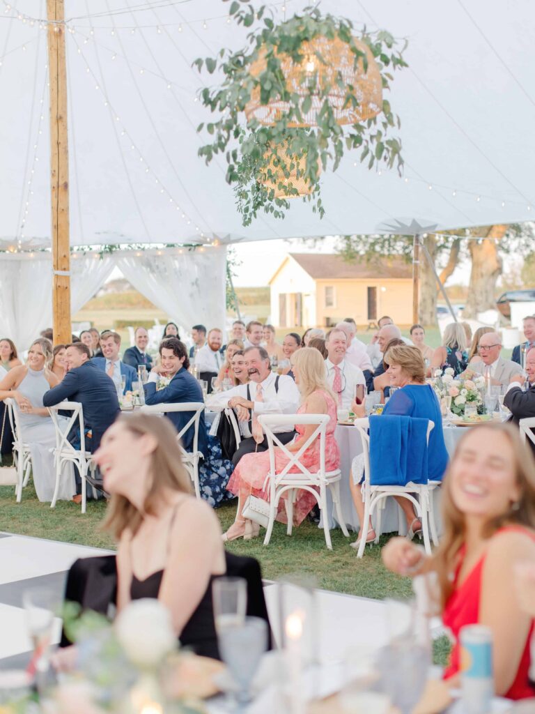Family laughing and clapping during wedding speeches at Newport reception.