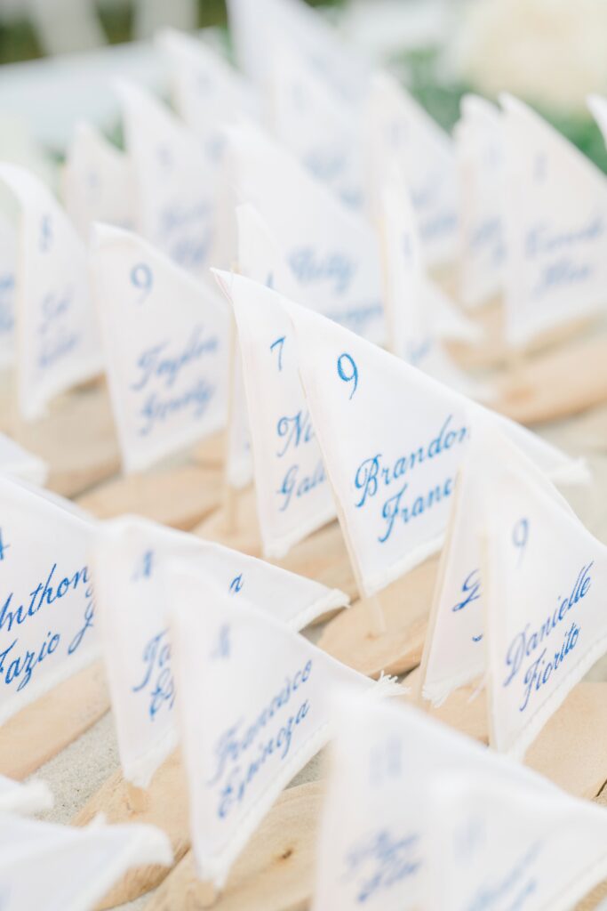 Personalized sailboat escort cards displayed during a seaside cocktail hour at Eisenhower House in Newport, Rhode Island.