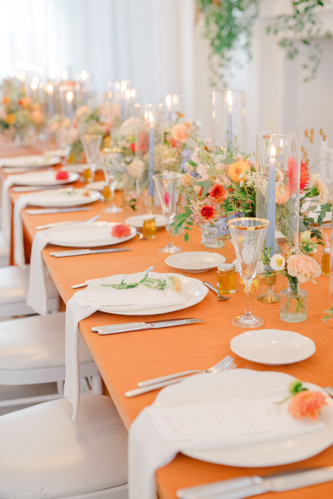 Head table at Belle Mer wedding reception with burnt orange linens, elegant place settings, and taper candles.