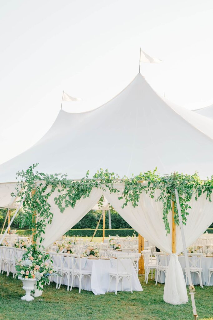 Reception tent glowing at sunset with pastel florals and a black-and-white dance floor at Eisenhower House Newport Rhode Island.