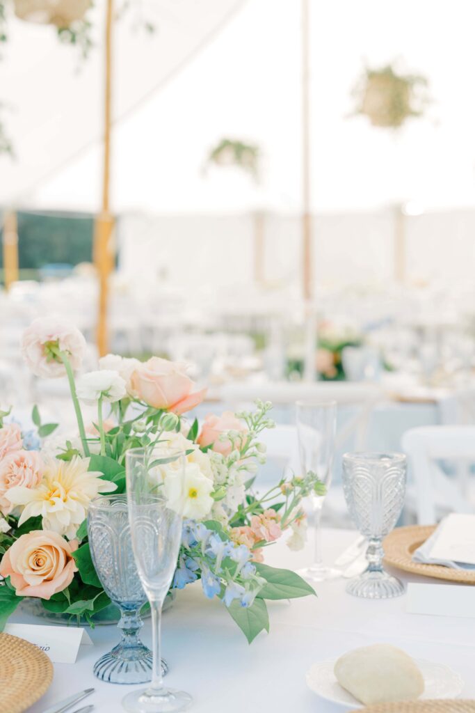 Romantic table settings with blue printed napkins and garden-inspired florals at a Newport wedding reception.