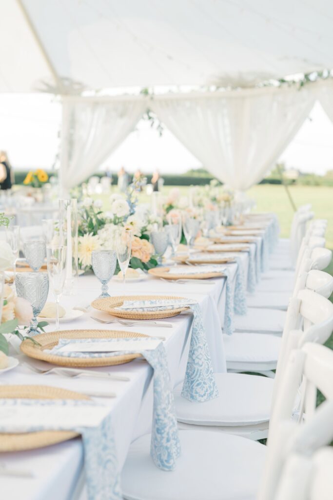 Long reception tables under tent draping, styled with romantic florals and coastal textures.