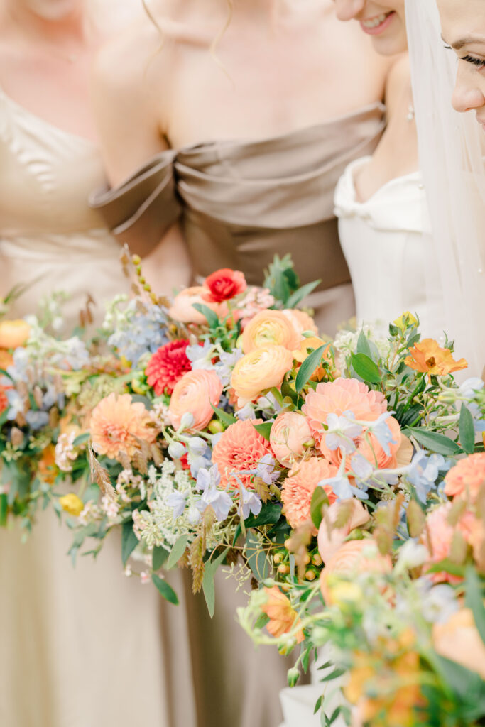 Vibrant orange, peach, and blue bridesmaid bouquet for Belle Mer coastal wedding.