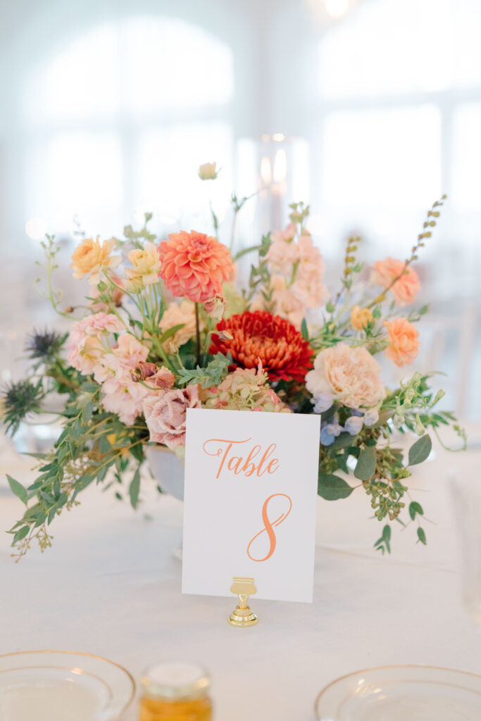 Table 8 centerpiece with vibrant florals and table number at Belle Mer wedding reception.