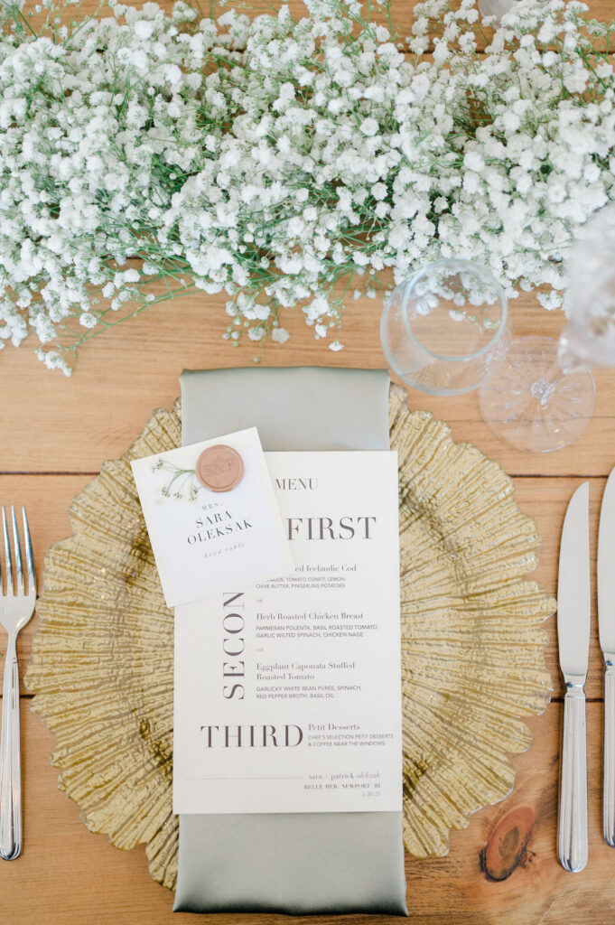Stylish place setting with gold charger and wedding menu at Belle Mer reception in Newport.