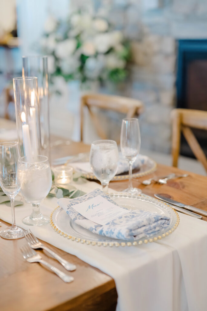 Elegant reception table setting with candles, white florals, and menus at Wentworth by the Sea.