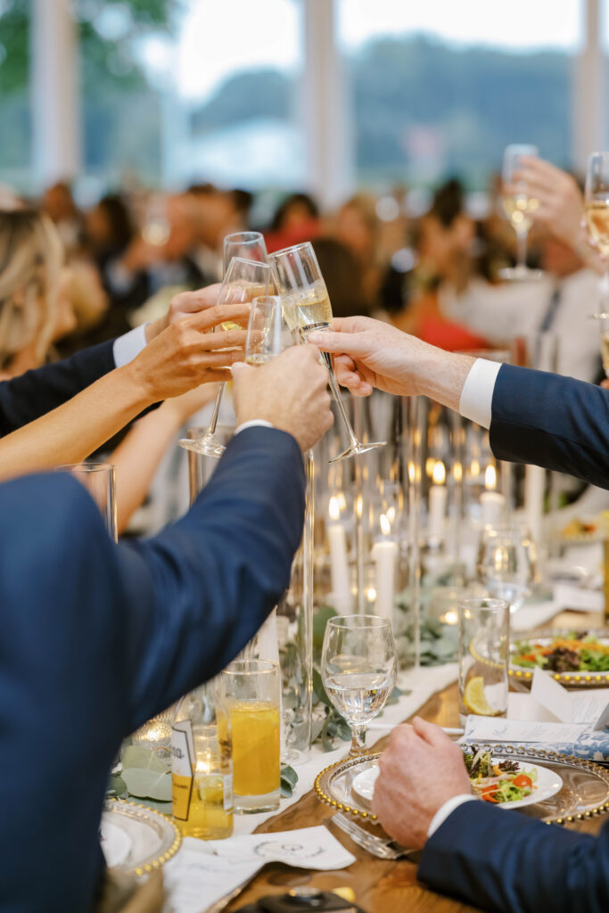 Champagne glasses raised during celebratory wedding toasts at Wentworth by the Sea reception.